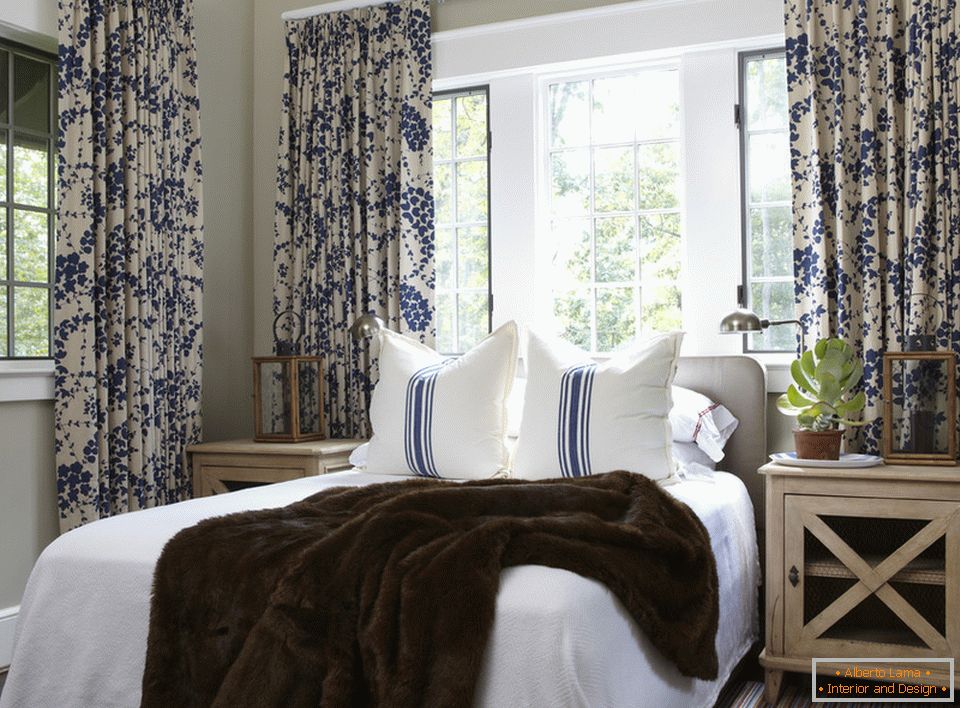 Сините цветя на завесите и ивиците на възглавниците хармонично се комбинират във вътрешността на спалнята