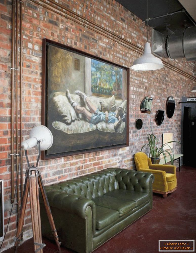 Голяма маслена живопис върху тухлена стена на таванско помещение в индустриален стил с ретро диван и фотьойл