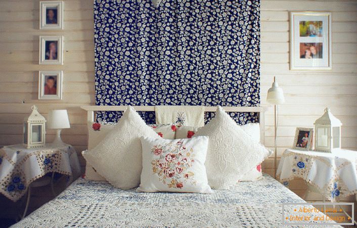 В съответствие с рустикалния стил, леглото е украсено с множество възглавници с контрастираща червена бродерия. Нощни шкафчета са покрити с покривка за маса с деликатни сини цветя.