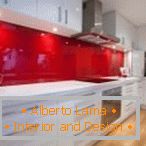 Бели мебели и червена престилка във вътрешността на кухнята