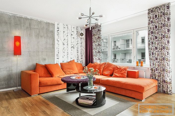 Скандинавският стил е присъщ на използването на топли цветове в интериорния дизайн. Мекият портокалов диван изглежда екологично на фона на стените на студено сив нюанс.