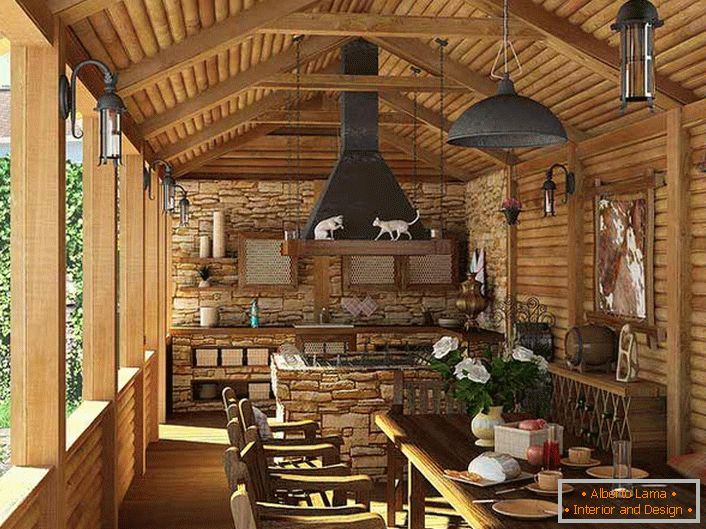 Малка кухня с барбекю на верандата на селска къща. Стилът на страната се доказва най-вече чрез украсата на стените и тавана с дървена рамка.