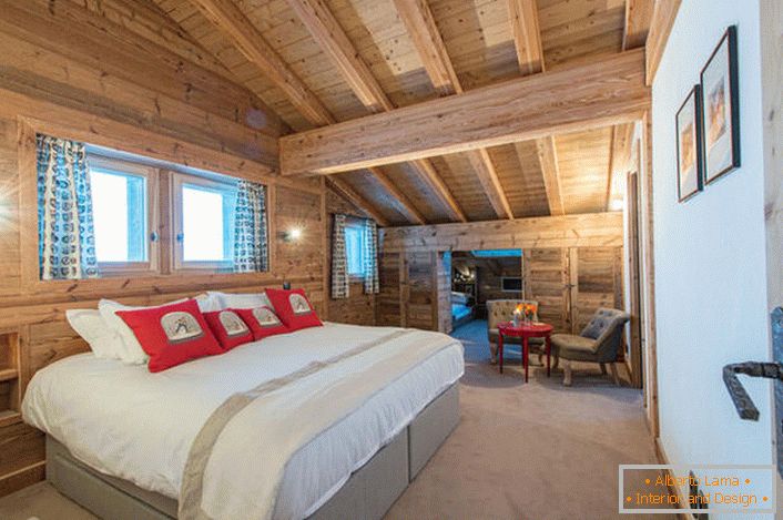 Просторна спалня на втория етаж на селска къща от дървена дървена къща. В соответствии со стилем кантри искусственный свет в комнате приглушен. 