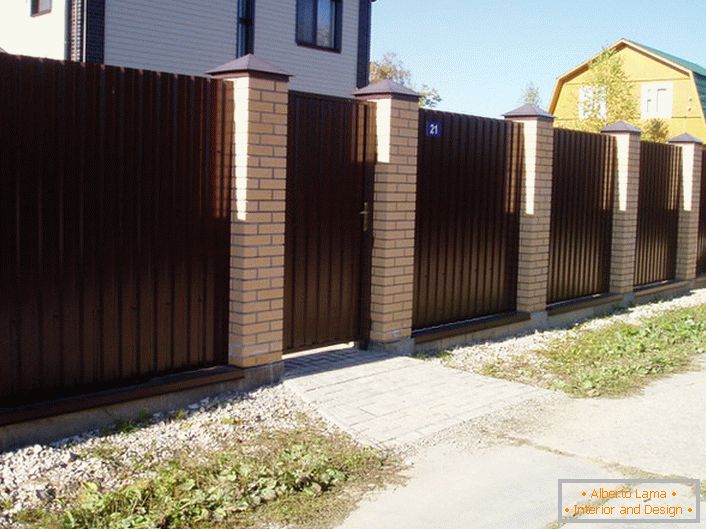 Модулната ограда е тъмнокафява, с тухлена облицовка - класика на жанра, ако говорим за дизайна на крайградски зони.