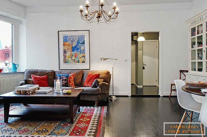 Стилната стая за гости в типичен градски апартамент е украсена със светли възглавници на дивана и килима. 