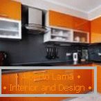 Плоска черна престилка в оранжевата кухня