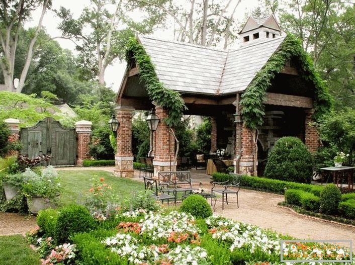Елегантната простота на отвореното беседка в стила на хижа изглежда органично в луксозна уютна градина. 