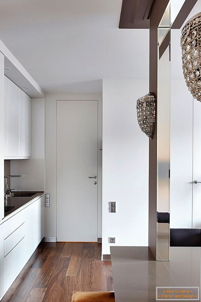 Бяла кухненска мебел, бяла входна врата и красив дървен паркет