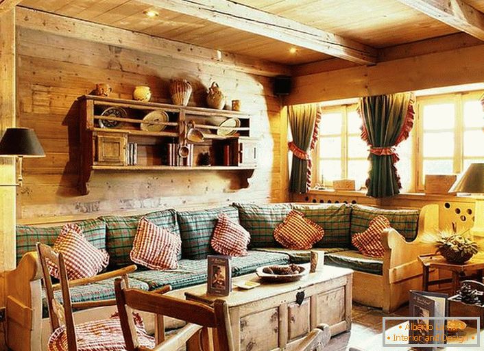 Дървена декорация на стените, контрастни възглавници на мека мека мебел, плътни завеси с провиснали прозорци. Уютна дневна в селски стил в провинцията.