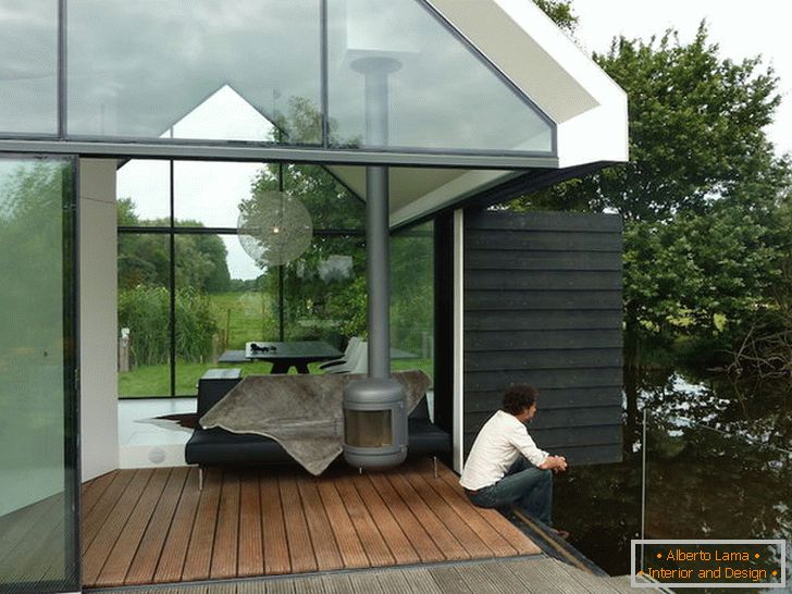 Тераса на малка стъклена къща до езерото в Холандия