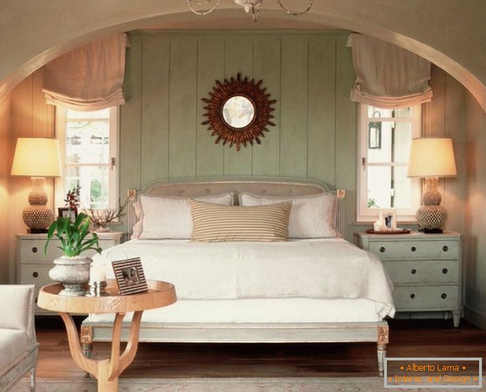 Семейна спалня в провинциален стил. Топлината на дома, както е възможно, се подчертава от меко, обемно легло, покрито с възглавници.