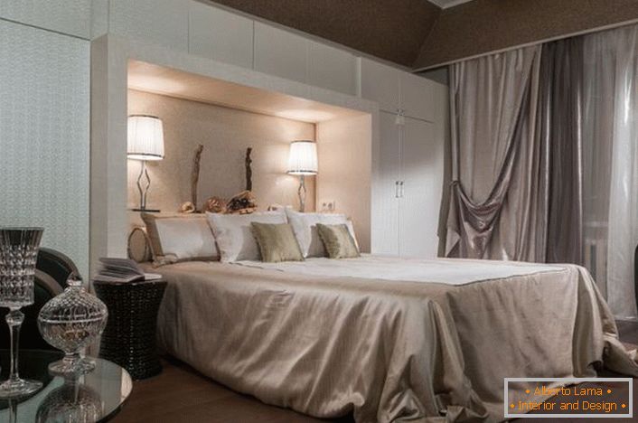 Интериор от благородна спалня в стил арт-деко. Вниманието е привлечено от функционалните шкафове с бял цвят. Благодарение на тях стаята става доста просторна и светла.